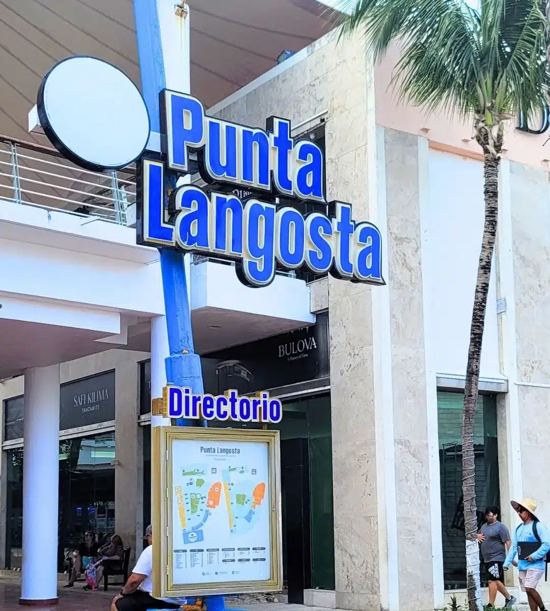 Punta Langosta cruise port with white and blue lighthouse and manicured streets.