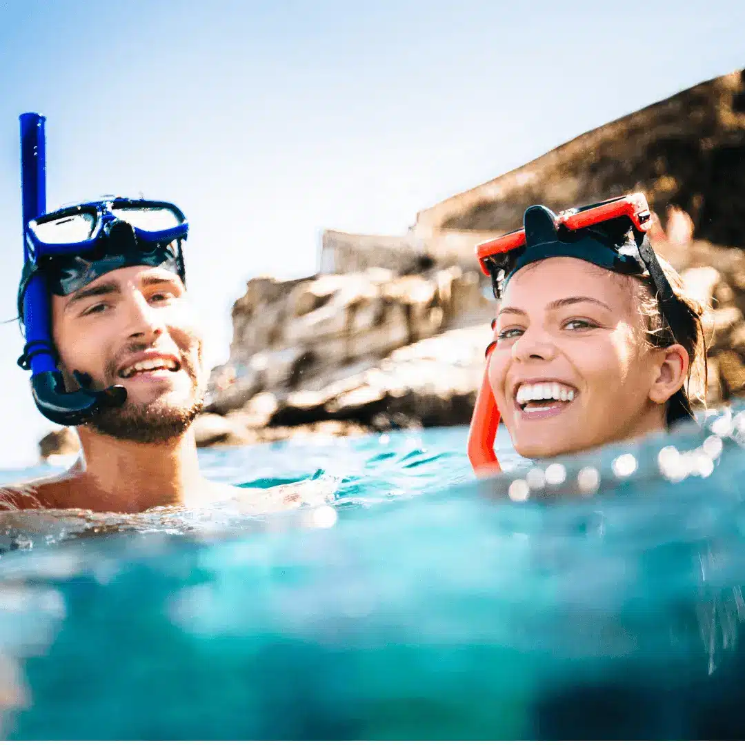 A happy couple smiling in the water while wearing snorkel gear. One of the most popular things to do